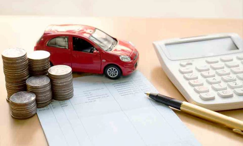 A red car sits on top of a pile of coins and a calculator, potentially indicating an accident claim involving the vehicle.